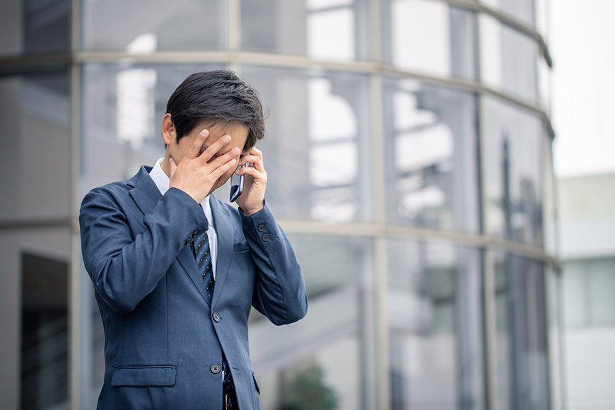 電話を手に困った表情をする男性