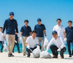 企業の地域社会貢献の一環で、環境保全の為従業員が海辺でごみを拾っている画像です。