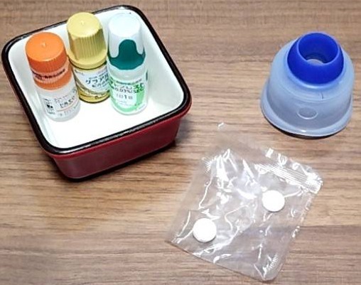 緑内障の為の眼圧を抑える目薬の点薬剤3本と、飲み薬錠剤2粒、点眼補助具の画像です。