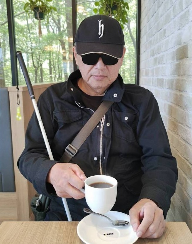 柏の葉公園内のドトールコーヒーで、視覚障害者が白杖を方に掛けながら、コーヒーを飲んでいる画像です。