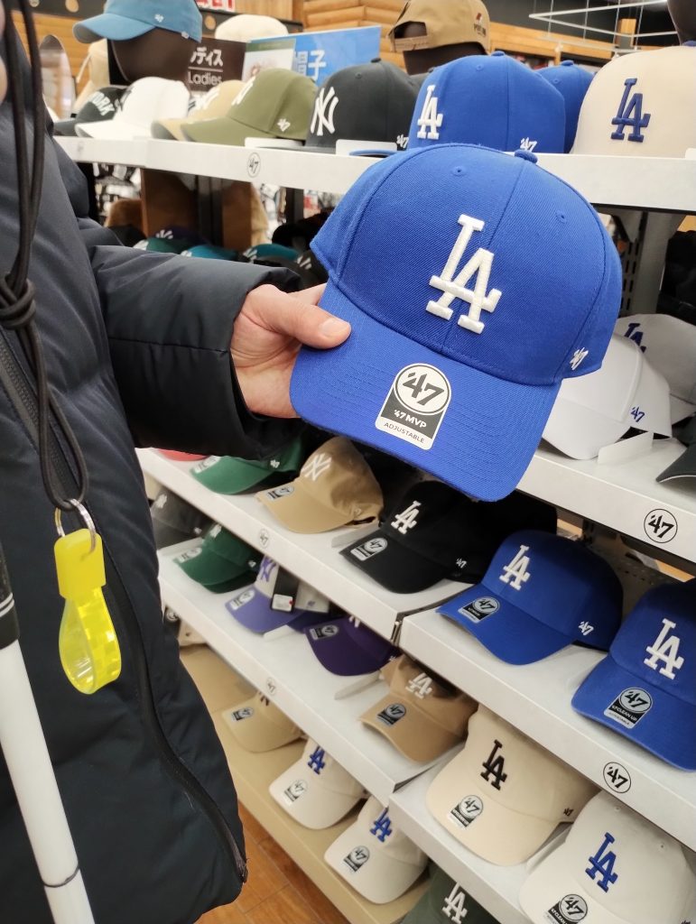 ロサンゼルスドジャース野球帽と白杖が写っている写真です。