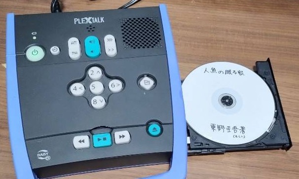 写真左側は視覚障害者用音声再生機「フレックストーク3」、写真右側はデイジー図書「東野圭吾、人魚の眠る家」の画像です。