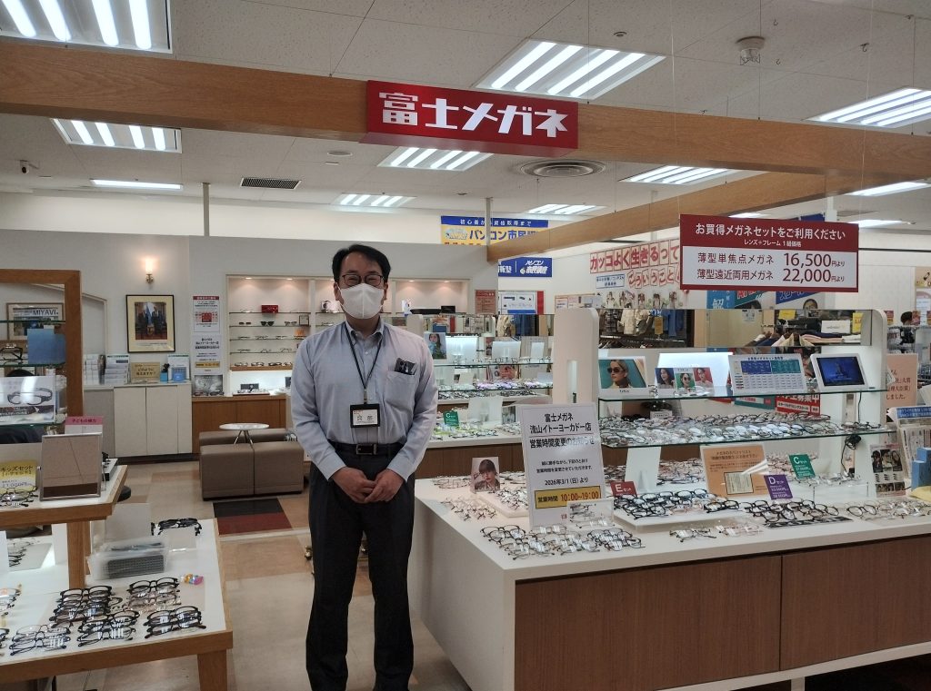 富士メガネ流山イトーヨーカドー店の店舗前で、満面の笑顔で副店長の阿部さんが立っている画像です。